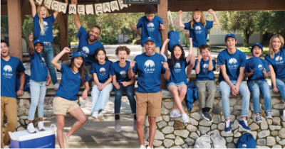 Summer camp attendees wearing matching camp tshirts outdoors.